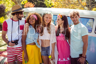 Happy friends standing together near campervan