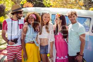 Happy friends standing together near campervan