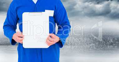 Mechanic holding up clipboard against blurry skyline