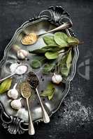 Dark culinary background with bay leaves, salt, pepper and garlic