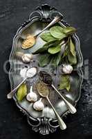 Dark culinary background with bay leaves, salt, pepper and garlic