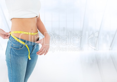 Woman mid section with measuring tape against blurry window