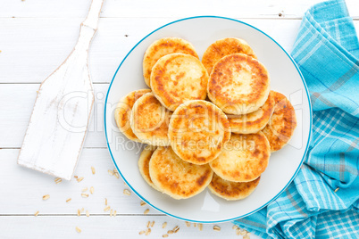 Cottage cheese pancakes with oats, syrniki on white rustic background