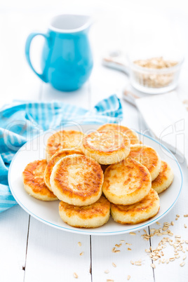 Cottage cheese pancakes with oats, syrniki on white rustic background