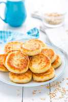 Cottage cheese pancakes with oats, syrniki on white rustic background