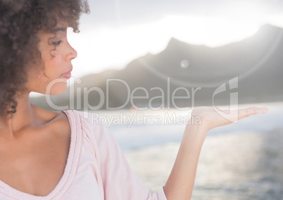 Woman with open palm hand in front of sea and mountains