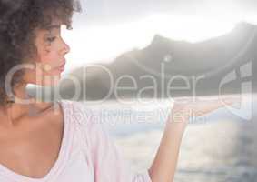 Woman with open palm hand in front of sea and mountains