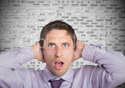 Man in lavendar shirt with hands on head against white brick wall