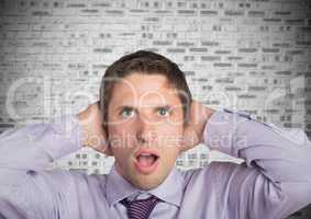 Man in lavendar shirt with hands on head against white brick wall