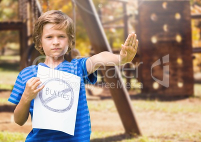 Sad boy holdingn anti bullying sign  against playground