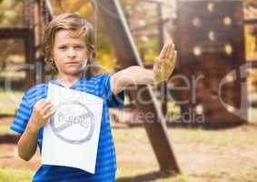 Sad boy holdingn anti bullying sign  against playground