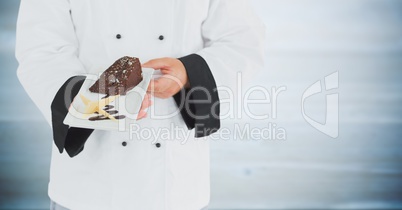 Chef with cake against blurry grey wood panel