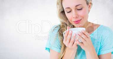 Close up of woman holding white cup against white wall