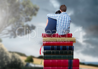 Couple sitting on Books stacked by romantic nature landscape