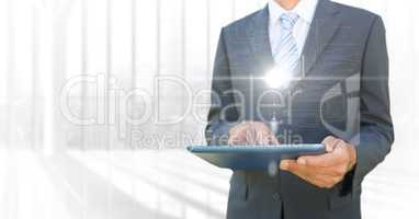 Business man mid section with tablet and white interface with flare against blurry window