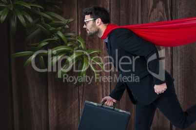 Confident business man super hero walking against wooden background with leaves