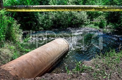 Water flows from the pipe into the river.