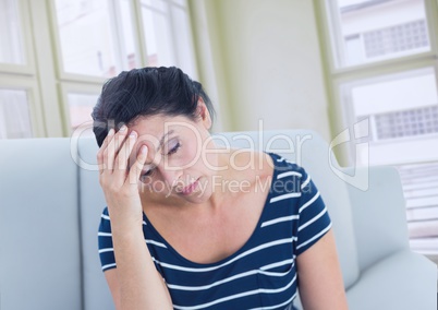 Sad stressed woman on couch by windows