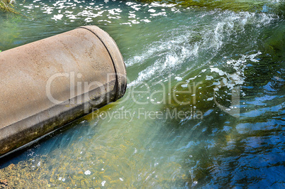 Water flows from the pipe into the river.