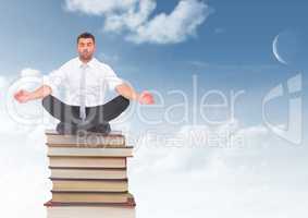Businessman meditating sitting on Books stacked by blue sky