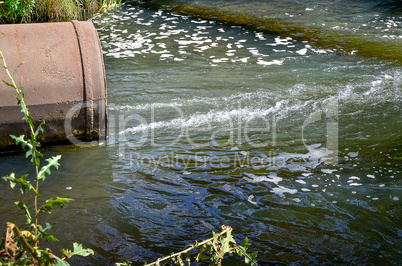 Water flows from the pipe into the river.