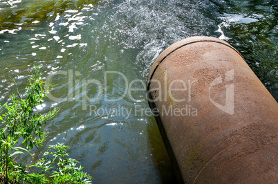 Water flows from the pipe into the river.