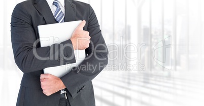 Business man mid section holding laptop against blurry window