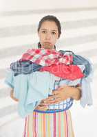 Tired upset woman with laundry basket against bright background