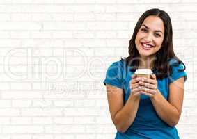Woman with blue tshirt and coffee cup against white brick wall