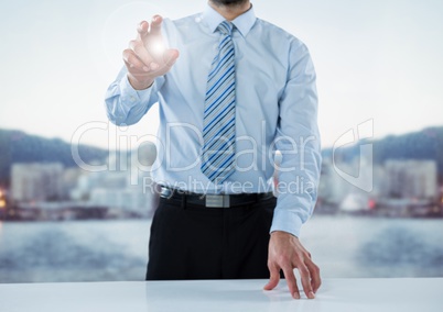 Business man mid section at desk with flare against blurry skyline