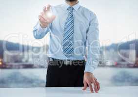 Business man mid section at desk with flare against blurry skyline