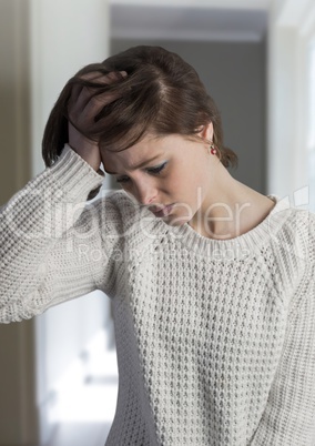 Sad depressed woman holding head against hall