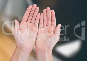 Hands open together reaching against blurred background