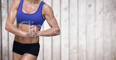 Muscular woman mid sections against blurry wood panel