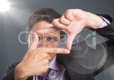 Close up of business man making rectangle behind flare against grey background