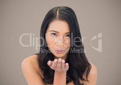 Woman blowing kiss against brown background