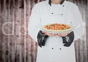Chef with pizza against blurry wood panel
