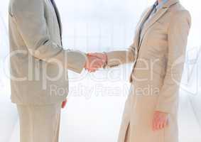Business people mid sections shaking hands against blurry window