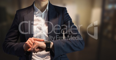 Business woman mid section looking at watch in blurry room