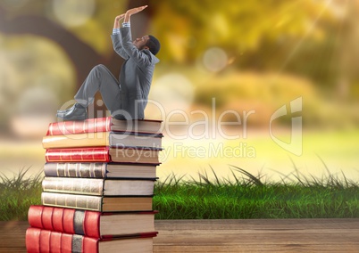 Businessman sitting on Books stacked by greenery nature