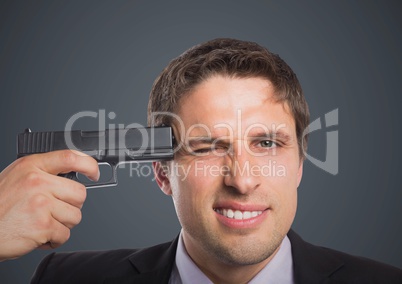 Close up of business man with gun to head against grey background