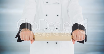 Chef with rolling pin against blurry grey wood panel