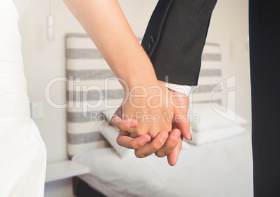 Wedding couple holding hands by bed