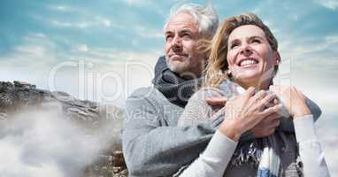 Couple in winter clothes against rocks and sky