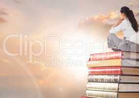 Businesswoman sitting on Books stacked by sun clouds