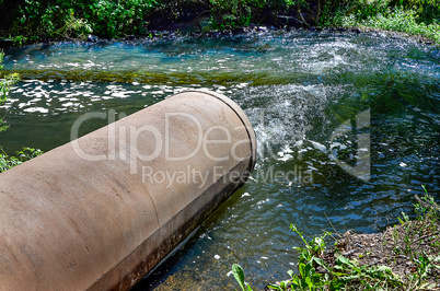 Water flows from the pipe into the river.