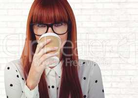 Woman with coffee cup over face against white brick wall