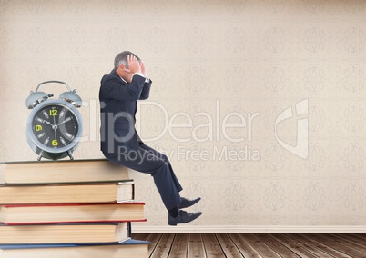 Stressed businessman sitting on Books stacked on shelf with clock