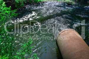 Water flows from the pipe into the river.