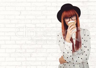Woman in polka dot shirt with coffee cup over face against white brick wall